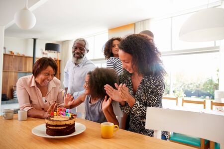 Multi-Generation Family Celebrating Granddaughters Birthday At Home With Cake And Candles