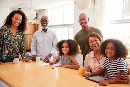 Portrait Of Grandparents Sitting At Table With Grandchildren Playing Games On Family Visit