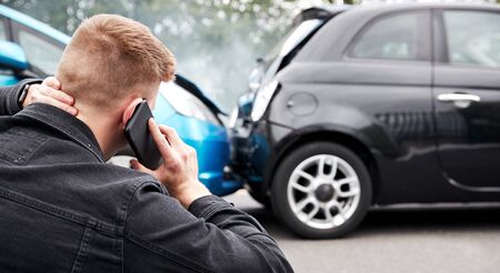 Young Male Motorist Involved In Car Accident Calling Insurance Company Or Recovery Serviceの写真素材