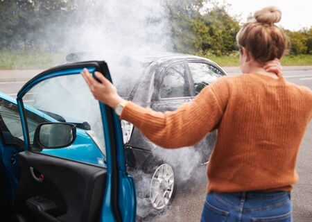 Rear View Of Female Motorist With Head Injury Getting Out Of Car After Crashの写真素材