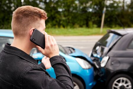 Young Male Motorist Involved In Car Accident Calling Insurance Company Or Recovery Serviceの写真素材