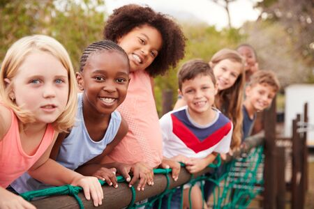Portrait Of Children Standing On Rope Bridge With Friends In Parkの写真素材