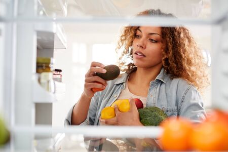 View Looking Out From Inside Of Refrigerator As Woman Opens Door And Packs Food Onto Shelvesの写真素材