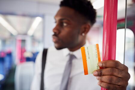 Businessman Standing In Train Commuting To Work Holding Ticketの写真素材