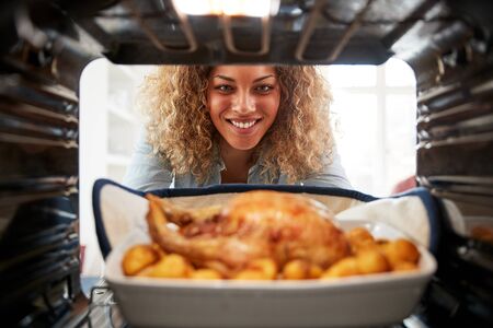 View Looking Out From Inside Oven As Woman Cooks Sunday Roast Chicken Dinnerの写真素材