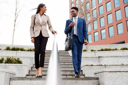 Businessman And Businesswoman Commuting To Work Walking Down Steps Outside Office Buildingの写真素材