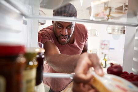 View Looking Out From Inside Of Refrigerator As Man Opens Door And Unpacks Shopping Bag Of Foodの写真素材