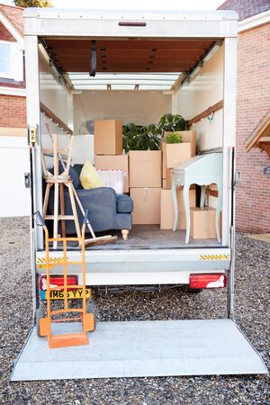 Removal Truck Waiting To Be Unloaded Outside New Home On Moving Day