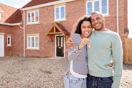 Portrait Of Couple Holding Keys Standing Outside New Home On Moving Dayの写真素材
