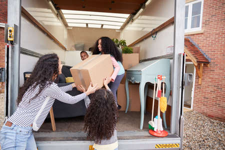 Mother And Children Unloading Furniture From Removal Truck Into New Homeの写真素材