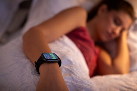 Woman Sleeping In Bed With Focus On Smart Watch She Is Wearingの写真素材