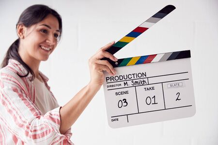 Female Videographer Holding Clapper Board On Video Film Production In White Studioの写真素材