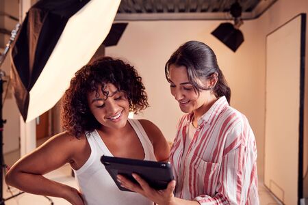 Photographer With Female Client Editing Images From Portrait Photo Shoot On Digital Tabletの写真素材