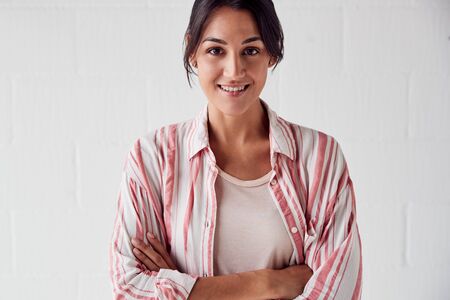 Portrait Of Smiling Casually Dressed Woman Standing Against White Brick Studio Wallの写真素材