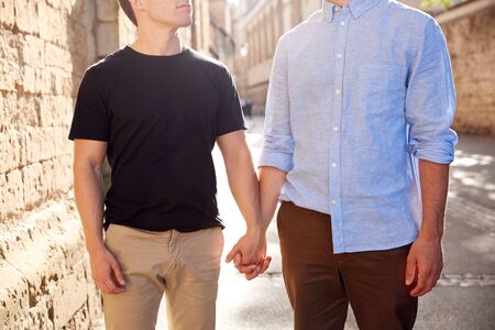 Close Up Of Male Gay Couple On Vacation Holding Hands Walking Along City Street