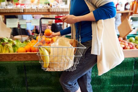 Close Up Of Female Customer With Shopping Basket Buying Fresh Produce In Organic Farm Shop