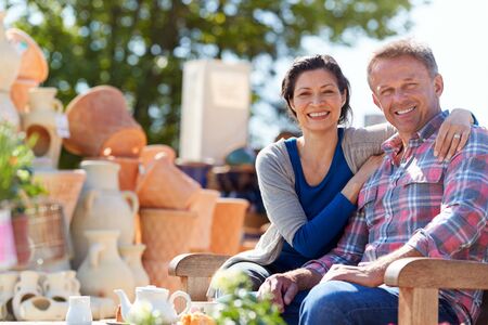 Portrait Of Mature Couple Sitting On Bench In Cafe Whilst Visiting Garden Centerの写真素材