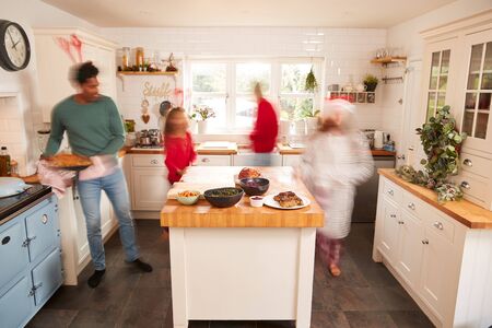 Motion Blur Shot Of Family In Kitchen Helping To Prepare Christmas Meal Togetherの写真素材