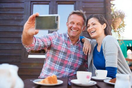 Mature Couple In Garden Center Cafe Taking Selfie On Mobile Phone