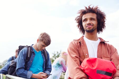 Young Man Waiting Behind Barrier At Entrance To Music Festival Site