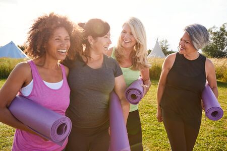 Group Of Mature Female Friends On Outdoor Yoga Retreat Walking Along Path Through Campsiteの写真素材
