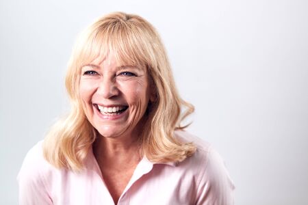 Studio Shot Of Smiling Mature Woman Against White Background At Camera