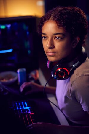 Teenage Girl With Headset Gaming At Home Using Dual Computer Screensの写真素材