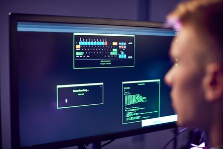 Male Teenage Hacker Sitting In Front Of Computer Screens Bypassing Cyber Securityの写真素材