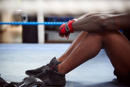 Close Up Of Tired Male Boxer Sitting In Boxing Ring In Gym After Training Sessionの写真素材