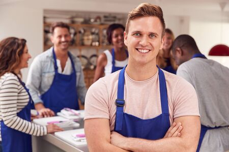 Portrait Of Smiling Man Wearing Apron Taking Part In Cookery Class In Kitchenの写真素材