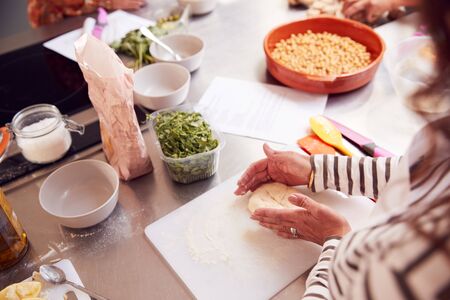 Close Up Of Female Teacher Demonstrating How To Use Dough To Make Flatbread In Cookery Classの写真素材