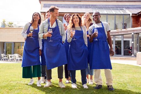 Group Portrait Of Men And Women Attending Cookery Class Relaxing Outdoors With Glass Of Wine