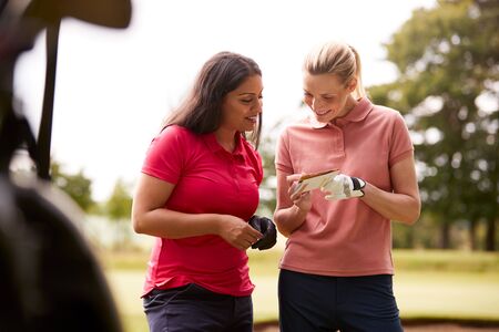 Two Women Playing Golf Marking Scorecard With  Buggy In Foregroundの写真素材