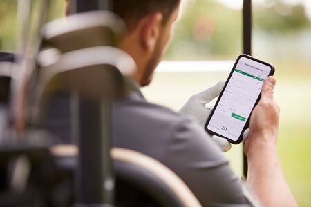 Close Up Of Male Golfer In Buggy Checking Score On Mobile Phone Appの写真素材