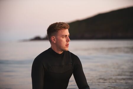 Man Wearing Wetsuit Sitting And Floating On Surfboard On Calm  Sea