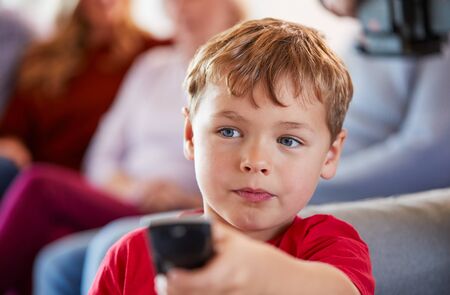 Boy Watching Television At Home With Multi-Generation Family Relaxing In Backgroundの写真素材