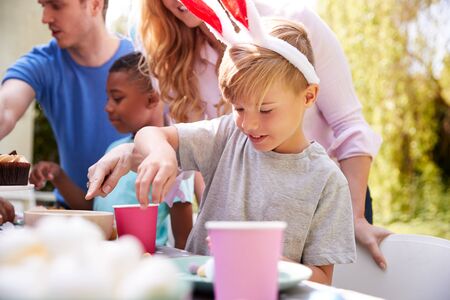 Parents With Children Wearing Bunny Ears Enjoying Outdoor Easter Party In Garden At Homeの写真素材