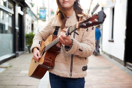 Close Up Of  Female Musician Busking Playing Acoustic Guitar  Outdoors In Streetの写真素材