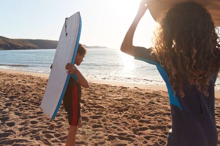 Children Wearing Wetsuits Carrying Bodyboards On Summer Beach Vacation Having Fun By Seaの写真素材