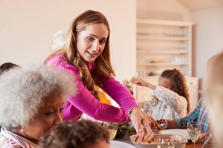 Mother Serving Food As Multi-Generation Family Meet For Meal At Homeの写真素材