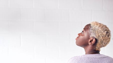 Rear View Of Young Woman Standing Against White Studio Wall