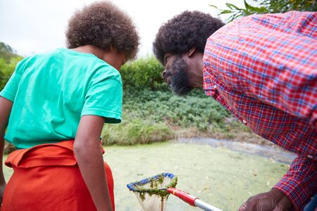 Adult Team Leader Showing Boy On Outdoor Activity Camp How To Catch And Study Pond Lifeの写真素材