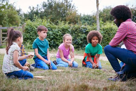 Team Leader Showing Group Of Children On Outdoor Camping Trip How To Make Fireの写真素材