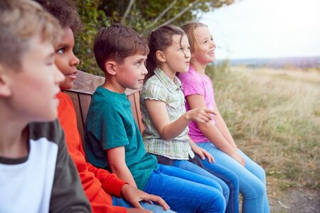 Group Of Children At Outdoor Activity Camp Resting On Bench During Walk Through Countrysideの写真素材