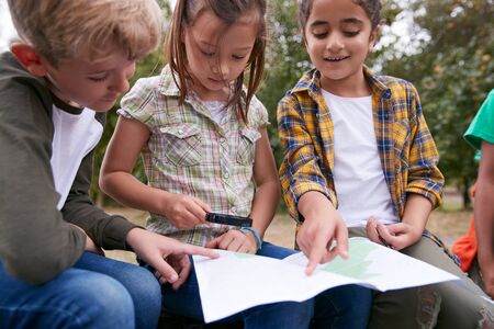 Group Of Children On Outdoor Activity Camping Trip Looking At Map Togetherの写真素材