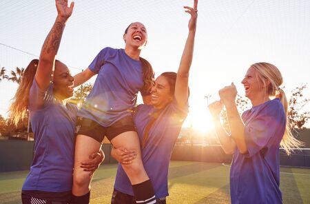 Womens Football Team Celebrating Winning Soccer Match Lifting Player Onto Shouldersの写真素材