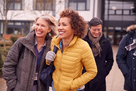 Group Of Smiling Mature Students Walking Outside College Buildingの写真素材