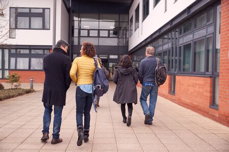 Group Of Mature Students Arriving Outside College Building
