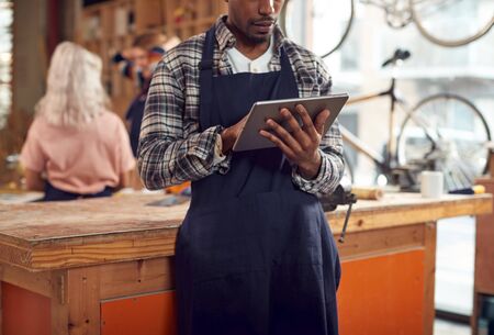Close Up Of Male Craftsman In Carpentry Workshop For Bamboo Bicycles Using Digital Tabletの写真素材