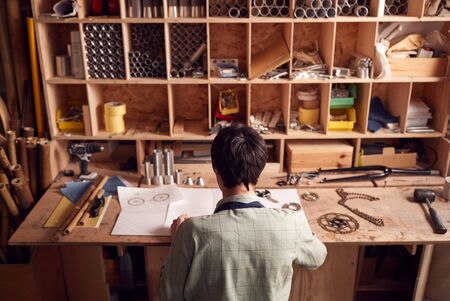 Rear View Of Designer In Workshop Looking At Components For Hand Built  Bamboo Bicycle Frame